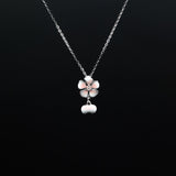 Silver necklace with a floral pendant on a black background