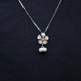 Silver necklace with a floral pendant on a dark background