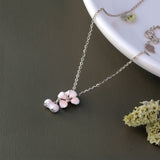 Necklace with pink floral pendant on a dark surface