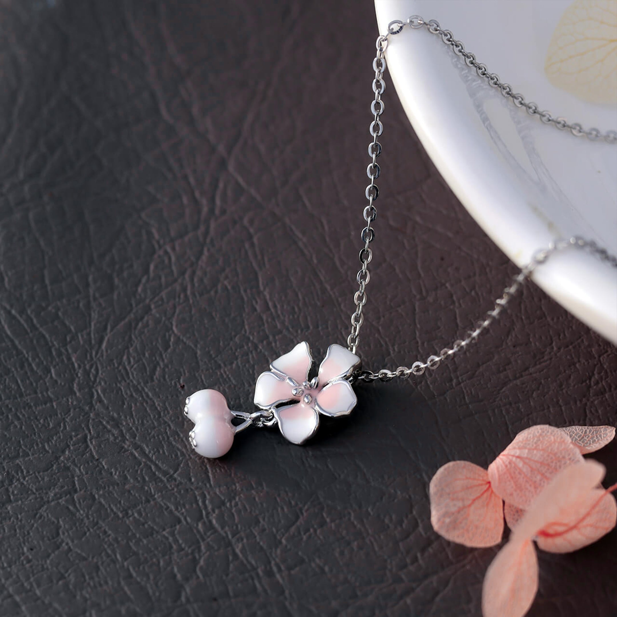 Necklace with cherry blossom pendant on a dark textured surface