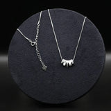 Two silver necklaces on a dark round surface