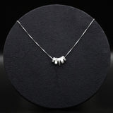 Silver necklace with a unique design on a black textured surface