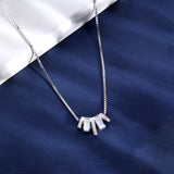 Silver necklace with a fan-shaped pendant on a blue fabric background