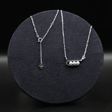 Two silver necklaces on a black textured surface