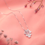 Silver necklace with a decorative pendant on a pink background