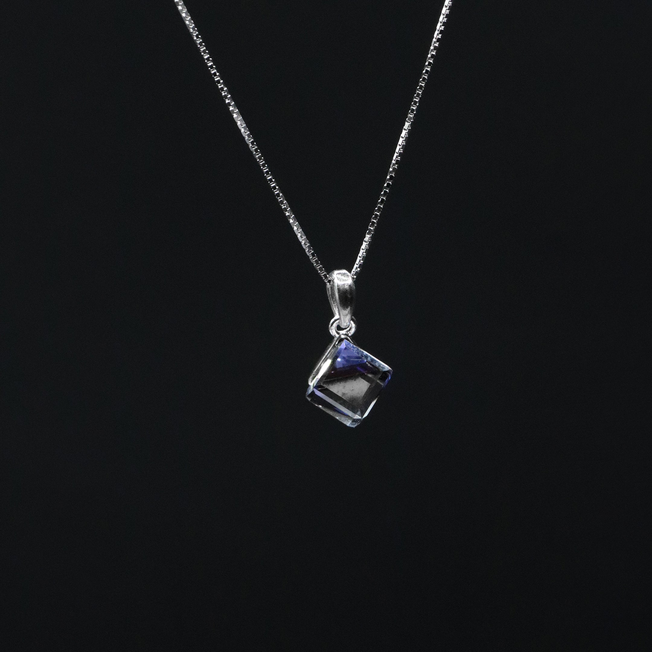 Silver necklace with a square pendant on a black background