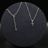 Two silver necklaces with gemstones on a dark textured surface
