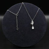 Silver necklace with a leaf pendant on a dark round stand