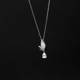 Silver necklace with a leaf and teardrop pendant on a black background