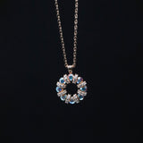 Necklace with a circular pendant featuring blue and clear stones on a black background