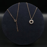 Gold necklace with a round pendant on a dark background