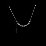 Silver necklace with small beads on a black circular stand