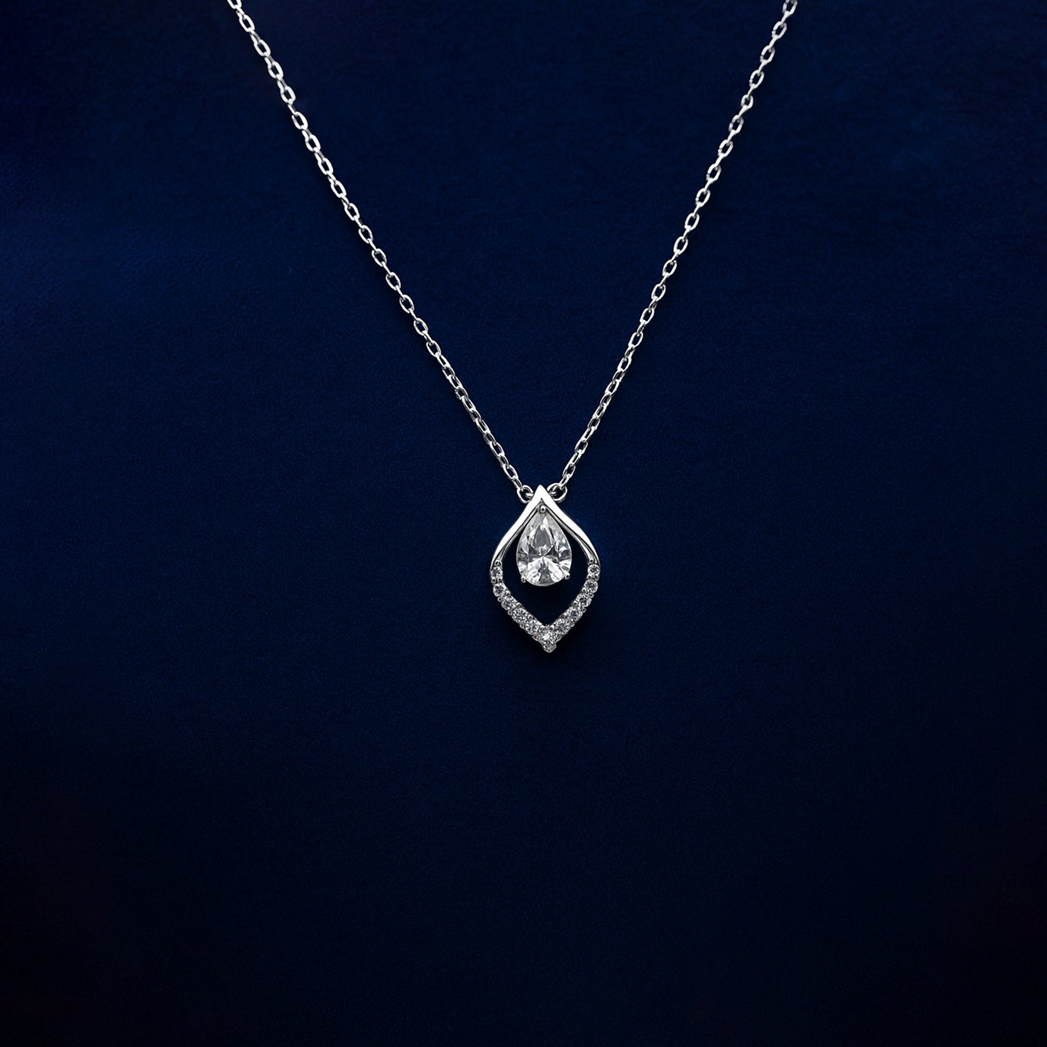 Silver necklace with a teardrop-shaped pendant on a dark blue background