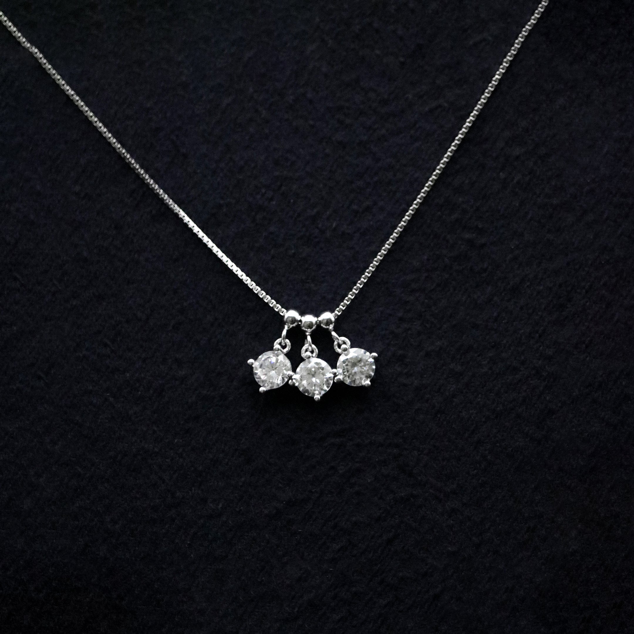 Silver necklace with three pendant drops on a black textured background