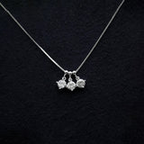 Silver necklace with three pendant drops on a black textured background