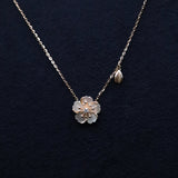 Gold necklace with a flower-shaped pendant on a dark background