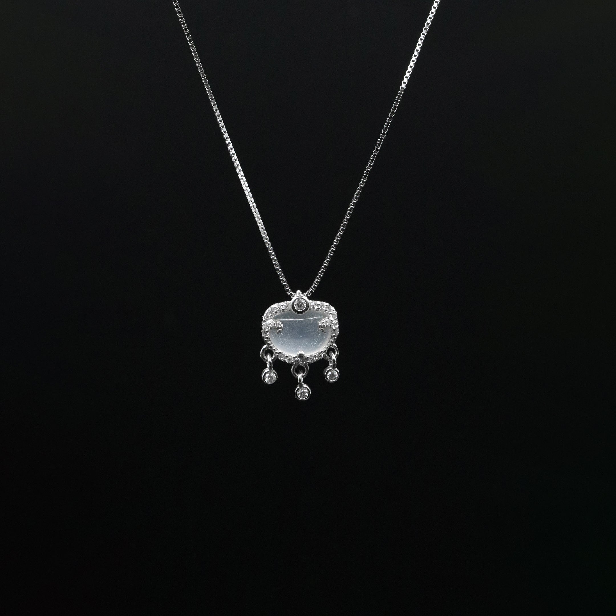 Silver necklace with a pendant on a black background