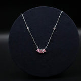Silver necklace with a pink pendant on a black background