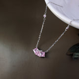 Necklace with a pink geometric pendant on a brown surface