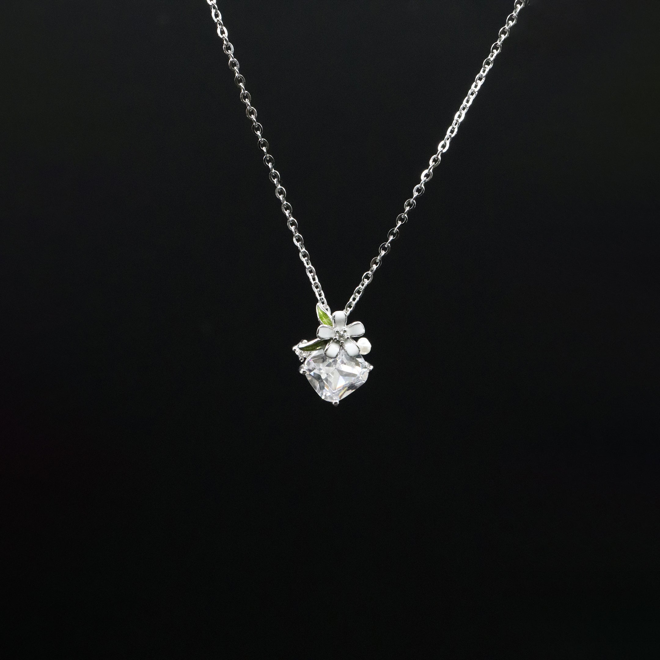 Silver necklace with a floral pendant on a black background