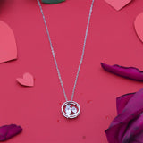Silver necklace with a heart pendant on a red background with heart shapes and purple flowers.