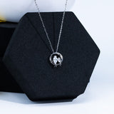 Silver necklace with a circular pendant on a black hexagonal stand.