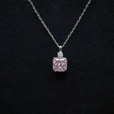 Pink diamond pendant on a chain against a black background