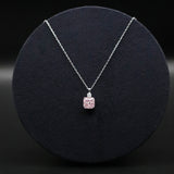 Necklace with a pink pendant on a black round cushion