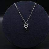 Silver necklace with a spiral pendant on a dark blue cushion
