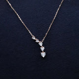 Rose gold necklace with heart-shaped diamonds on a dark blue background