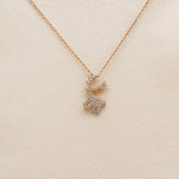 Rose gold deer-shaped necklace with diamonds on a beige background
