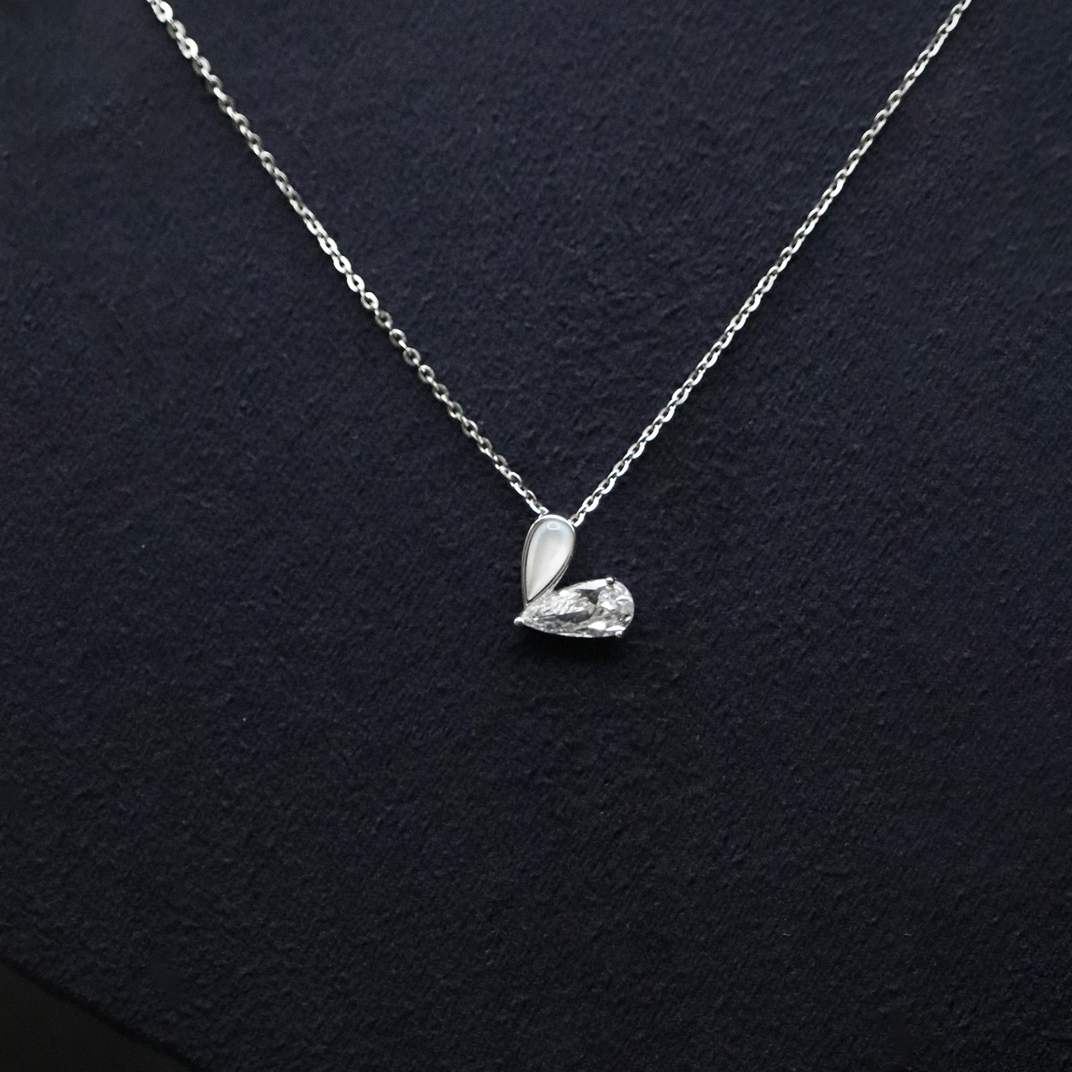 Silver necklace with a heart-shaped pendant on a dark background
