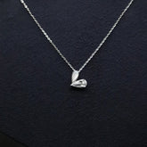 Silver necklace with a heart-shaped pendant on a dark background