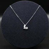 Silver necklace with a heart-shaped pendant on a black round stand