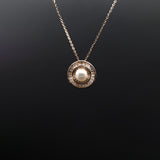 Gold necklace with a round pendant on a black background