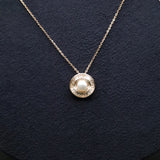 Gold necklace with a pearl pendant on a dark background