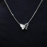 Silver butterfly necklace on a dark textured background