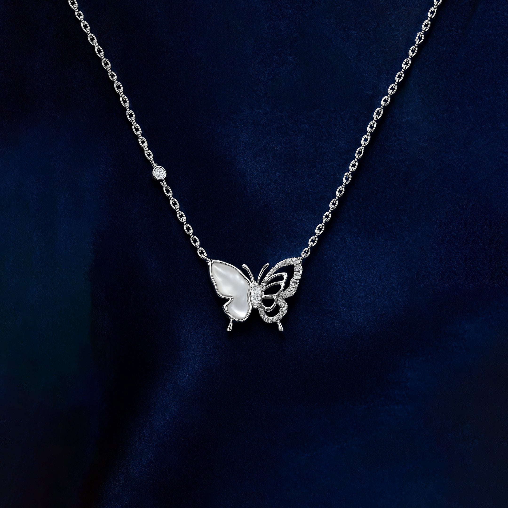 Silver butterfly necklace on a dark blue background