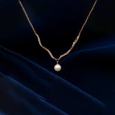 Gold necklace with a pearl pendant on a dark blue fabric background