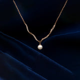 Gold necklace with a pearl pendant on a dark blue fabric background