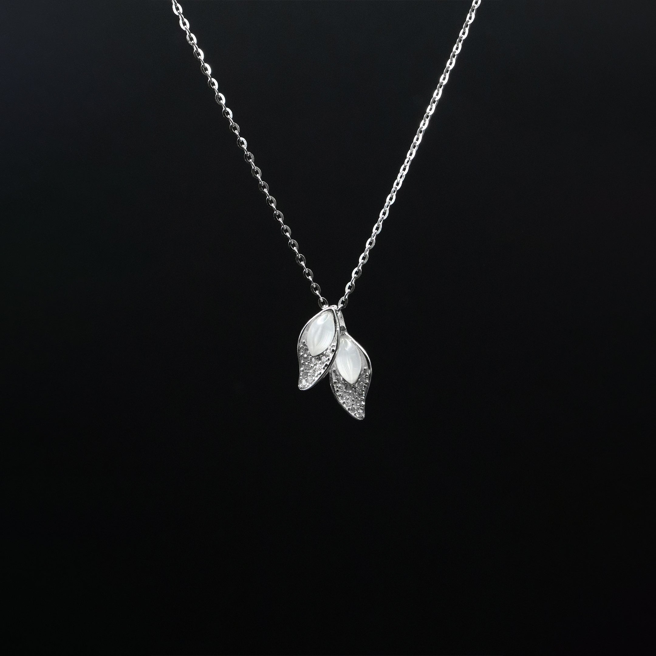 Silver necklace with leaf-shaped pendants on a black background