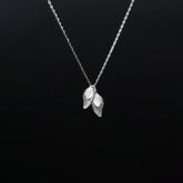 Silver necklace with leaf-shaped pendants on a black background