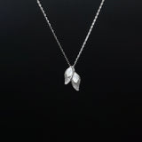 Silver necklace with leaf-shaped pendants on a black background
