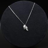 Silver necklace with leaf pendants on a black background