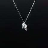 Silver necklace with leaf-shaped pendant on a black background