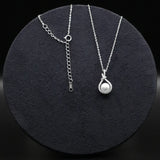Silver necklace with a pearl pendant on a black round stand