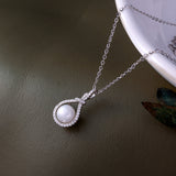 Pearl necklace with silver chain on a dark surface