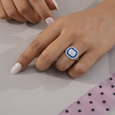 Hand wearing a ring with a blue and white gemstone on a neutral background