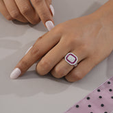 Close-up of a hand wearing a diamond ring on a neutral background