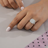 Close-up of a hand wearing a silver ring with a diamond on a light background